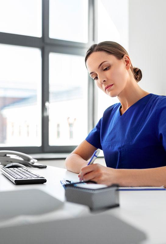 femme concentrée et sérieuse du personnel administratif au comptoir qui prend des notes sur un dossier patient